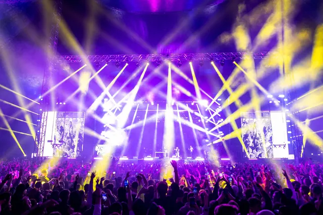 Işıklı konser sahnesi ve seyirciler — sanatçı ve ekip transferi
